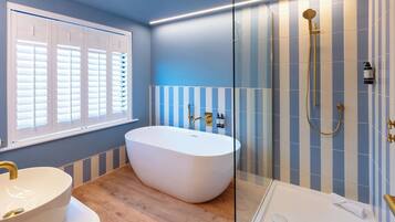 A modern bathroom with a freestanding bathtub, a sink with a gold faucet, and a shower with a gold showerhead.