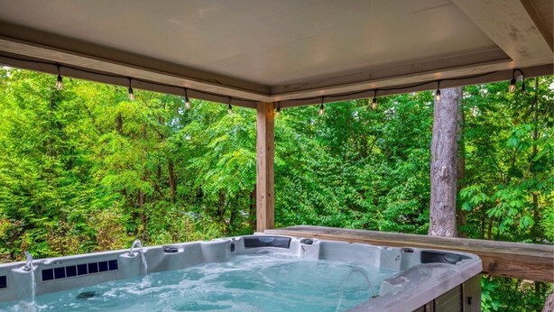 Ein Whirlpool mit einer Holterrasse und Blick auf dichtes Grün.