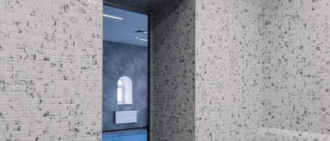 A hallway with mosaic tiled walls and a dark wooden floor, leading to a pool area.