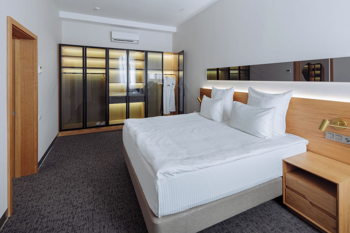 Quarto de hotel moderno com uma cama grande, um closet espaçoso e uma mesa de cabeceira.