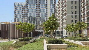 A modern apartment building with balconies, a well-maintained garden, and a clear sky. - WelHome - Beautiful 1BR Apt in Dubai Hills with City View (Dubai)