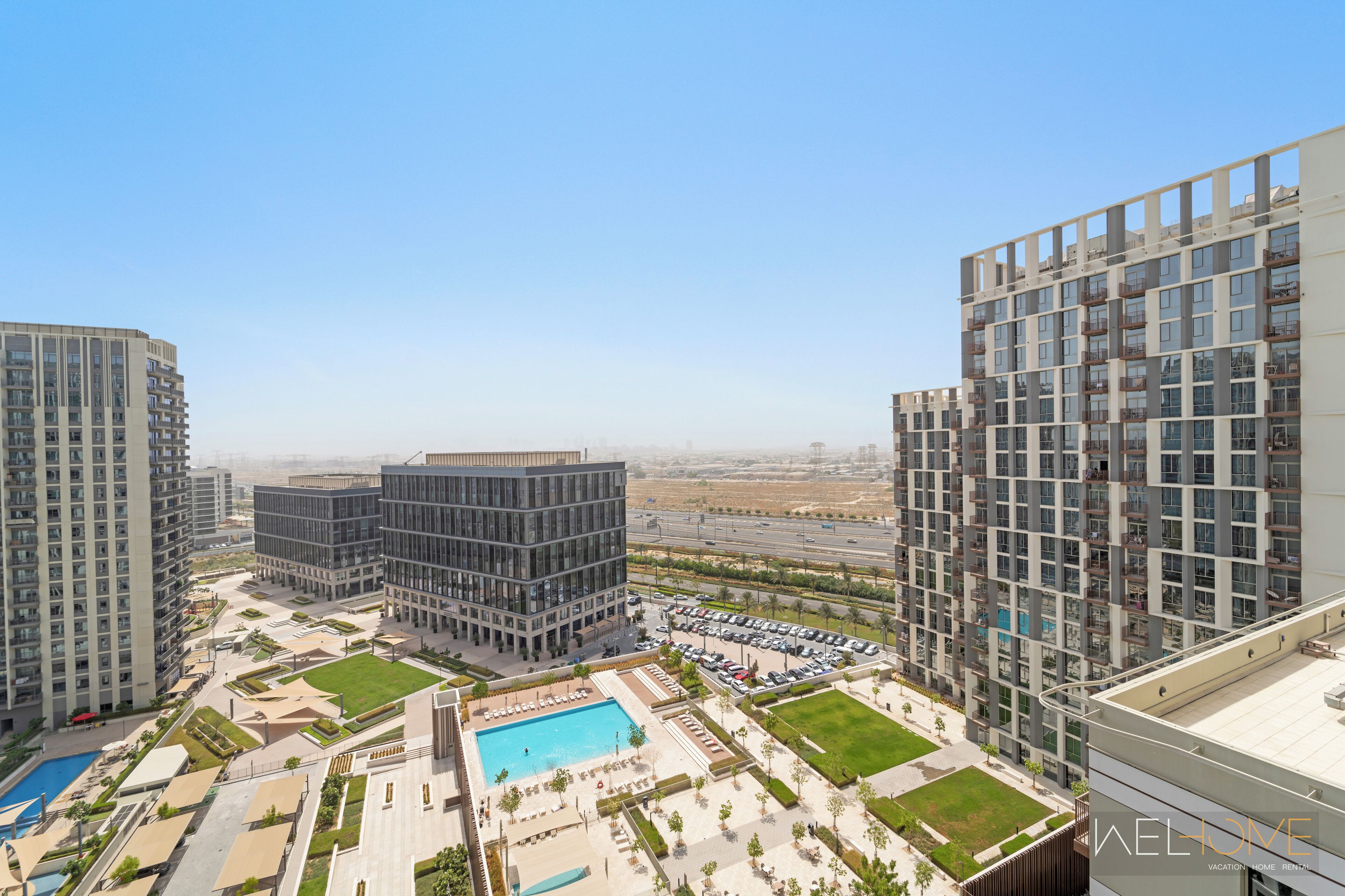 Un edificio residencial alto con varios balcones, un patio central con piscina y un área de estacionamiento.