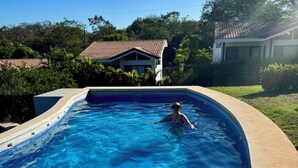 A swimming pool with clear blue water, surrounded by a concrete deck and lush greenery. - Costa Rican Private Villa | monkeys visit the trees! (Venado)