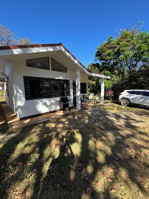 A modern house with a patio, a barbecue grill, and a car parked outside.