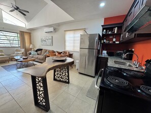 A modern kitchen with a refrigerator, stove, and dining area with chairs and a table.