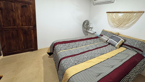 A bedroom with a bed, a ceiling fan, an air conditioning unit, a hammock, and a wooden door. - Costa Rican Private Villa | monkeys visit the trees! (Venado)