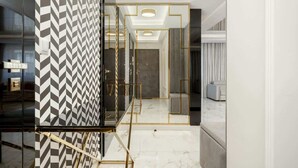 Un interior moderno con una pared de diseño geométrico, una escalera con detalles dorados y un suelo de mármol.