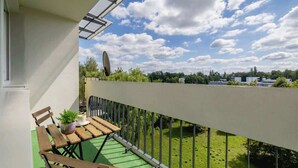 A balcony with a green artificial grass floor, wooden furniture, and a metal railing. - Spacious Apartment for 6 Persons | Balcony | 3 Bedrooms (Kraków)