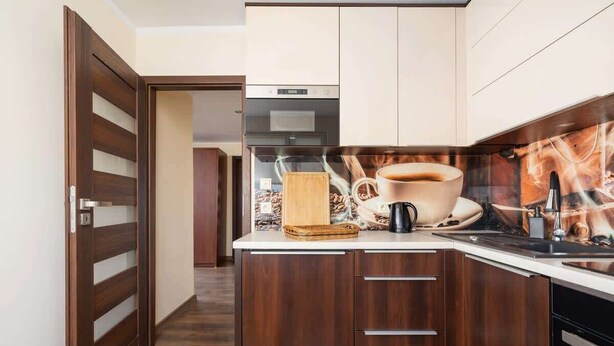 A modern kitchen with wooden cabinets, a stainless steel range hood, and a coffee maker on the counter. - Spacious Apartment for 6 Persons | Balcony | 3 Bedrooms (Kraków)