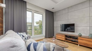 Un salon moderne comprenant un canapé, une table basse, un téléviseur et un meuble de rangement en bois.