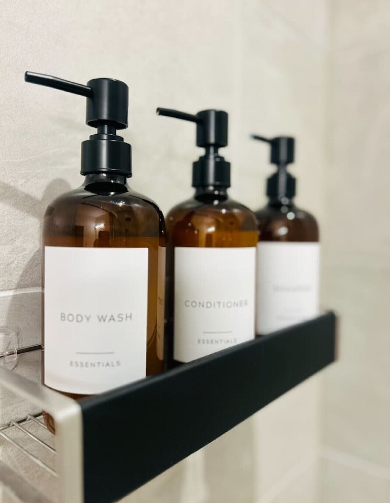 Tres botellas de gel de baño y acondicionador sobre un estante negro.