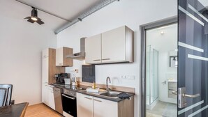Una cocina compacta con electrodomésticos modernos, un comedor con mesa y sillas, y vistas al baño contiguo.