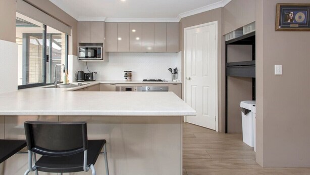 A modern kitchen with a central island, built-in appliances, and a dining area with a chair.