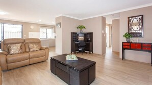 A spacious living room with a leather sofa, a coffee table, a desk, and a cabinet.