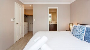 A hotel room with a bed, a bedside table, a lamp, and a view of the bathroom.
