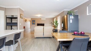 A modern kitchen with a dining area, including a wooden table and chairs, a sofa, and a refrigerator.