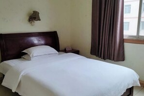 Una cama bien hecha con sábanas blancas en una habitación con cabecera de madera.