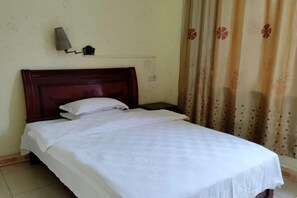 Una cama individual con cabecera de madera, una mesita de noche y una lámpara fijada a la pared.