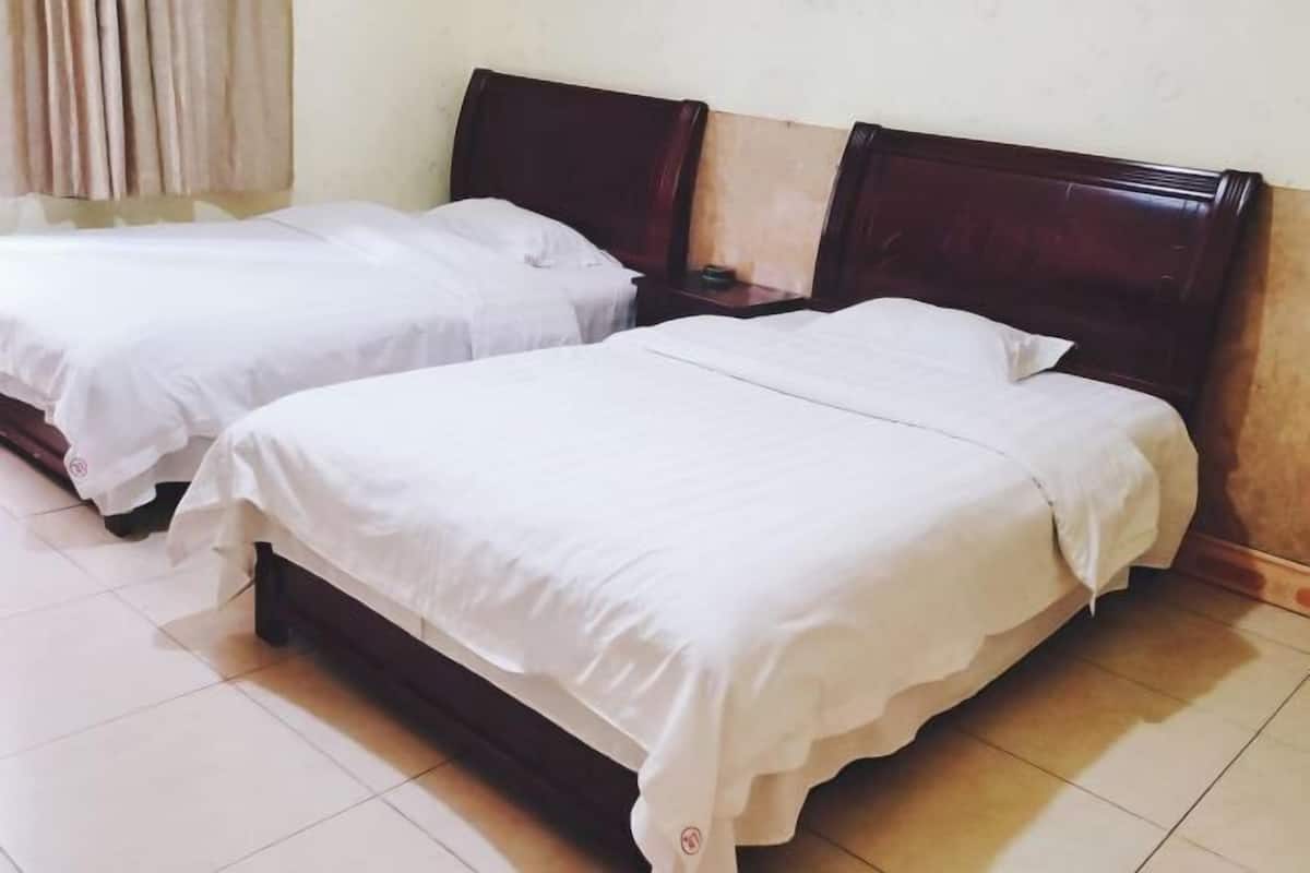 Two single beds with wooden headboards in a room with tiled flooring.