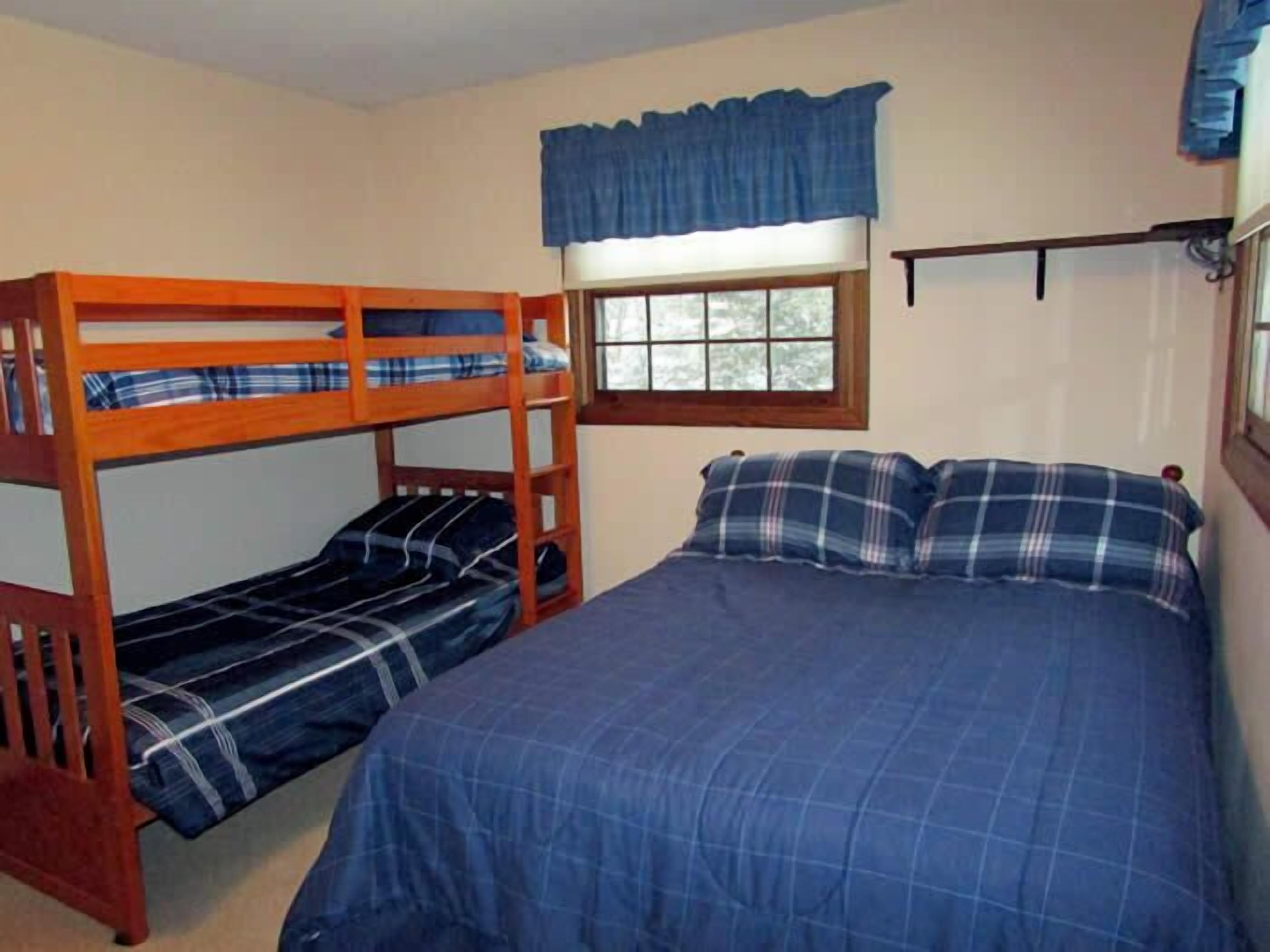 Ein Zimmer mit einem Etagenbett und einem Einzelbett, beide mit Karo-Bettwäsche.