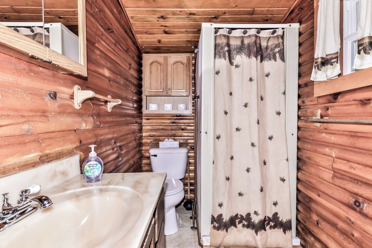 Ein Badezimmer einer Holzhütte mit Waschbecken, Toilette und Schrank.