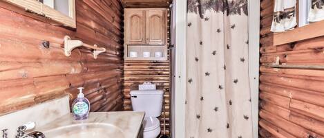 Ein Badezimmer einer Holzhütte mit Waschbecken, Toilette und Schrank.