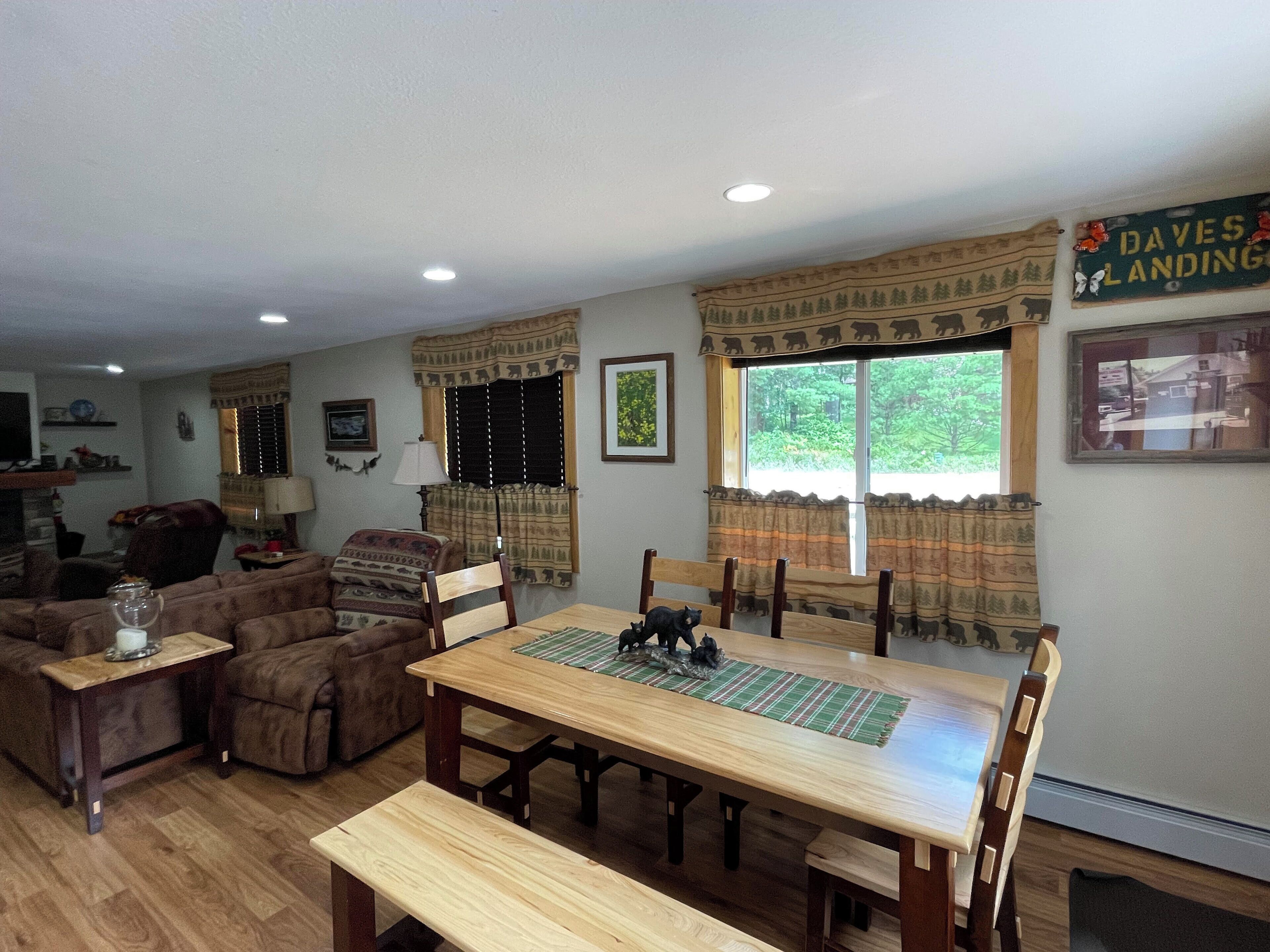 A cozy living room with a wooden dining table, two chairs, a sofa, and a TV.