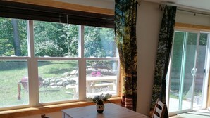 Un comedor con mesa y sillas, ventanas amplias y vistas a un jardín.