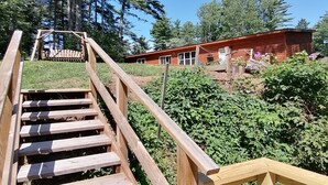Una escalera de madera que lleva a una cabaña rodeada de follaje.