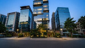 A modern hotel with a glass facade, a prominent entrance, and a sign reading 'AQUILA A-152'. - Aquila Grand Suites (Noida)