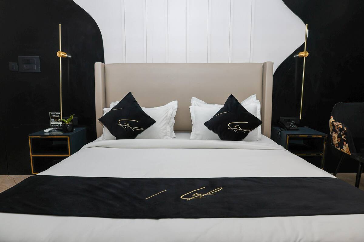 A bed with a black and white bedspread, two black pillows with gold text, and a gold accent on the headboard.