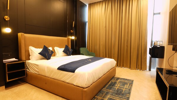 Una habitación de hotel con una cama grande, una mesita de noche, una silla, un escritorio y una cortina.