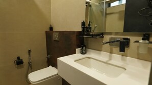 A bathroom with a white sink, a mirror, and a shower. - Aquila Grand Suites (Noida)