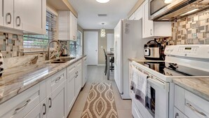 A modern kitchen with white cabinets, a marble countertop, a built-in oven, and a microwave. - Family Retreats 5 minutes to the beach (Tarpon Springs)