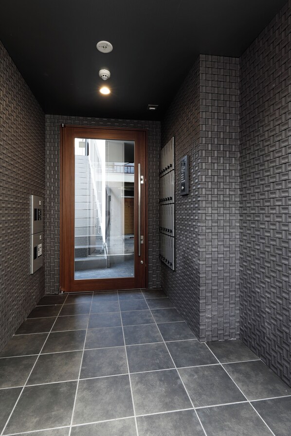 A hallway with a wooden door, tiled walls, and a tiled floor.