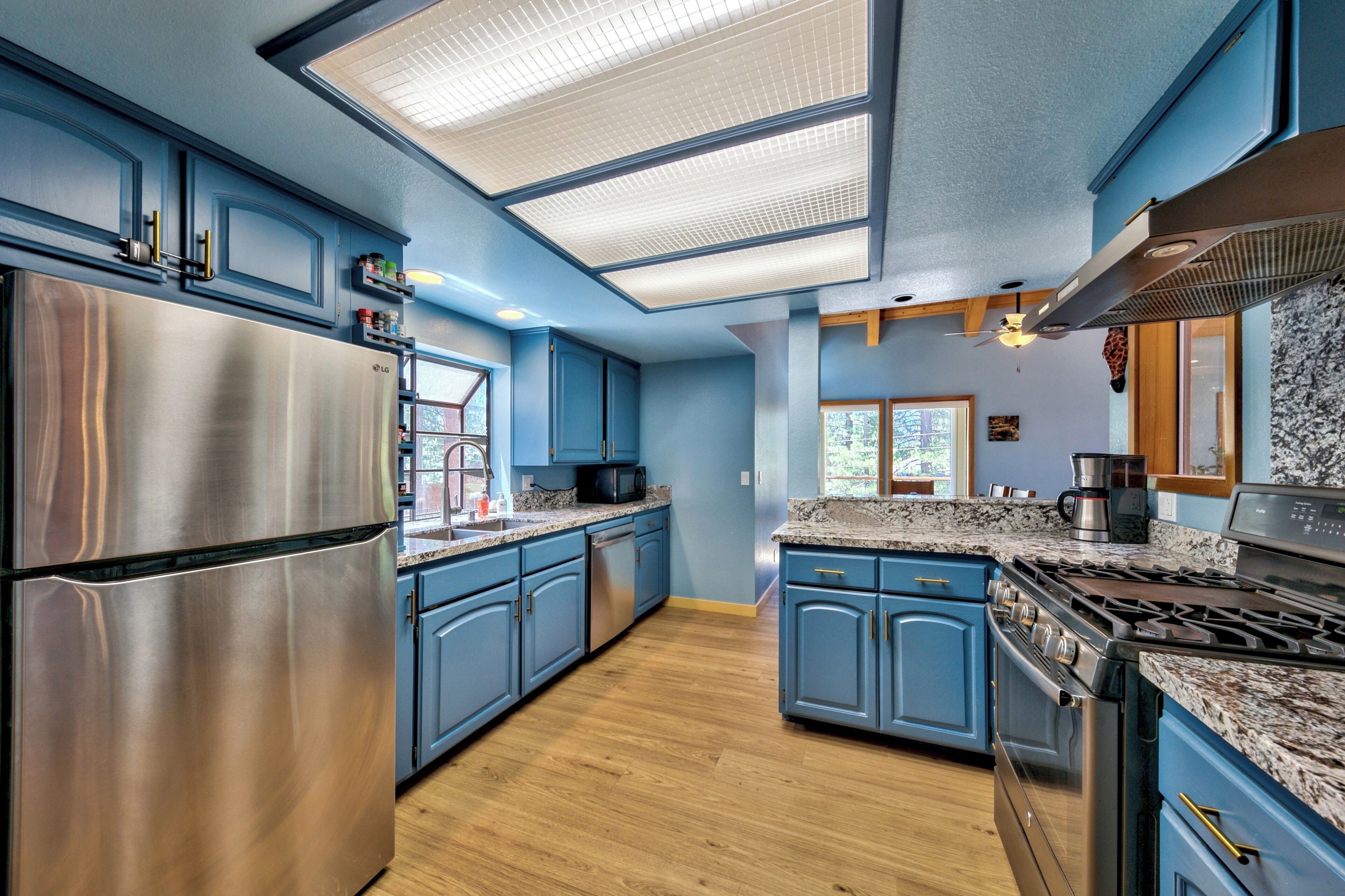 Una cocina moderna con gabinetes azules, electrodomésticos de acero inoxidable y una encimera de granito.