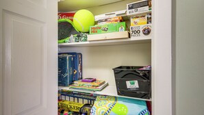 A shelf with various board games, puzzles, and a tennis ball. - Waterfront Biloxi Condo: Gulf-view Balcony! (Biloxi)