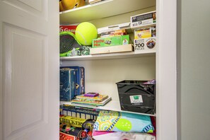 A shelf with various board games, puzzles, and a tennis ball. - Waterfront Biloxi Condo: Gulf-view Balcony! (Biloxi)