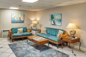A living room with two sofas, a coffee table, a lamp, and wall art. - Waterfront Biloxi Condo: Gulf-view Balcony! (Biloxi)