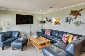 A living room with a sofa, coffee table, and decorative wall art. - Waterfront Biloxi Condo: Gulf-view Balcony! (Biloxi)
