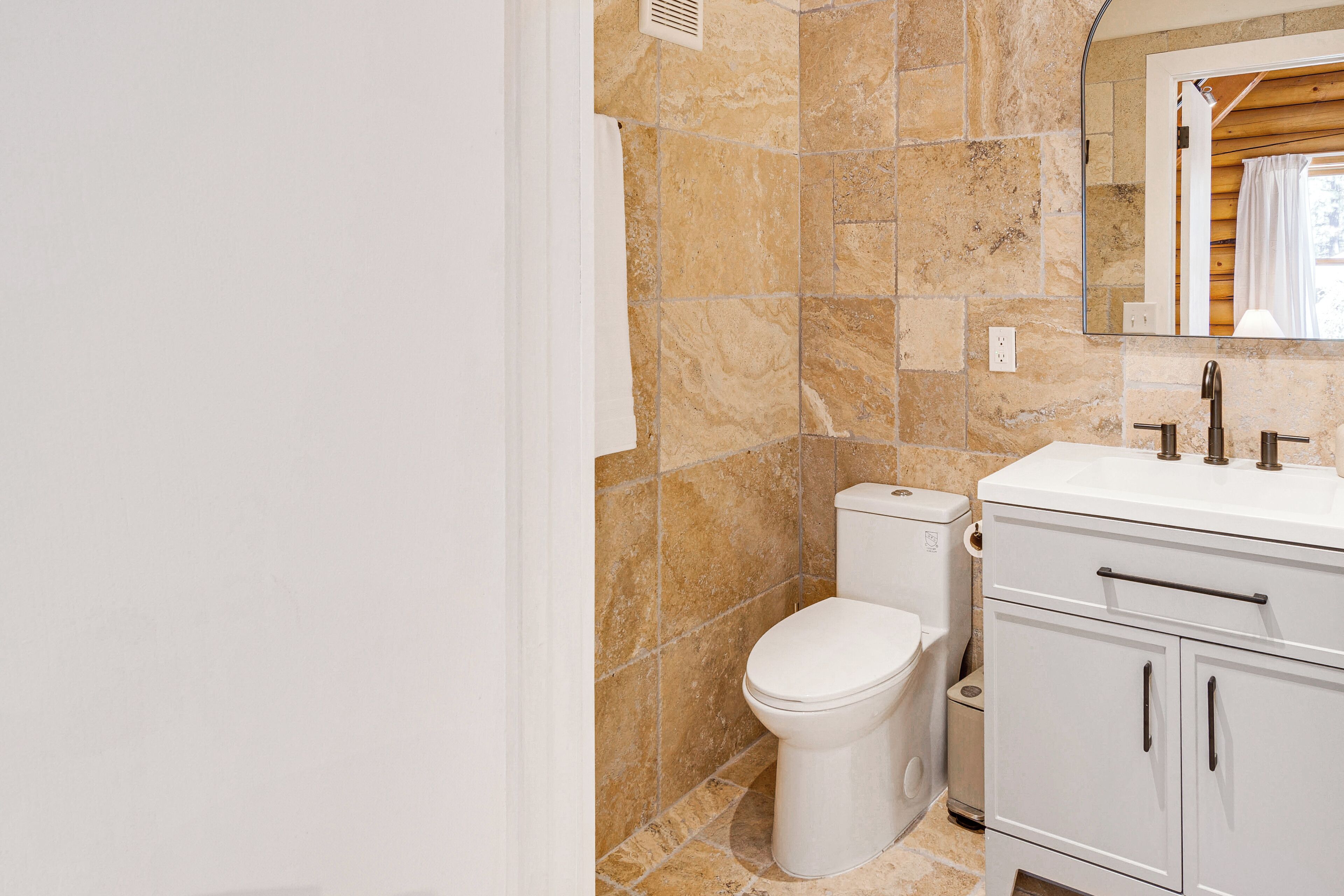 A bathroom with a toilet, sink, and cabinet.