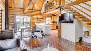 Interior espacioso de una cabaña de troncos con cocina moderna, comedor y sala de estar acogedora con chimenea.