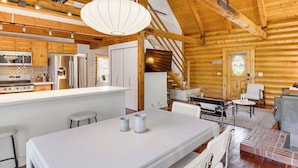 Interior moderno de una cabaña de troncos con cocina, comedor y zona de estar.
