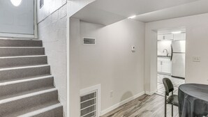 A staircase leading to a landing, a dining area with a table and chair, and a kitchen visible through an open doorway. - Cozy Sturgis Retreat - Walk to Main St & Saloons! (Sturgis)