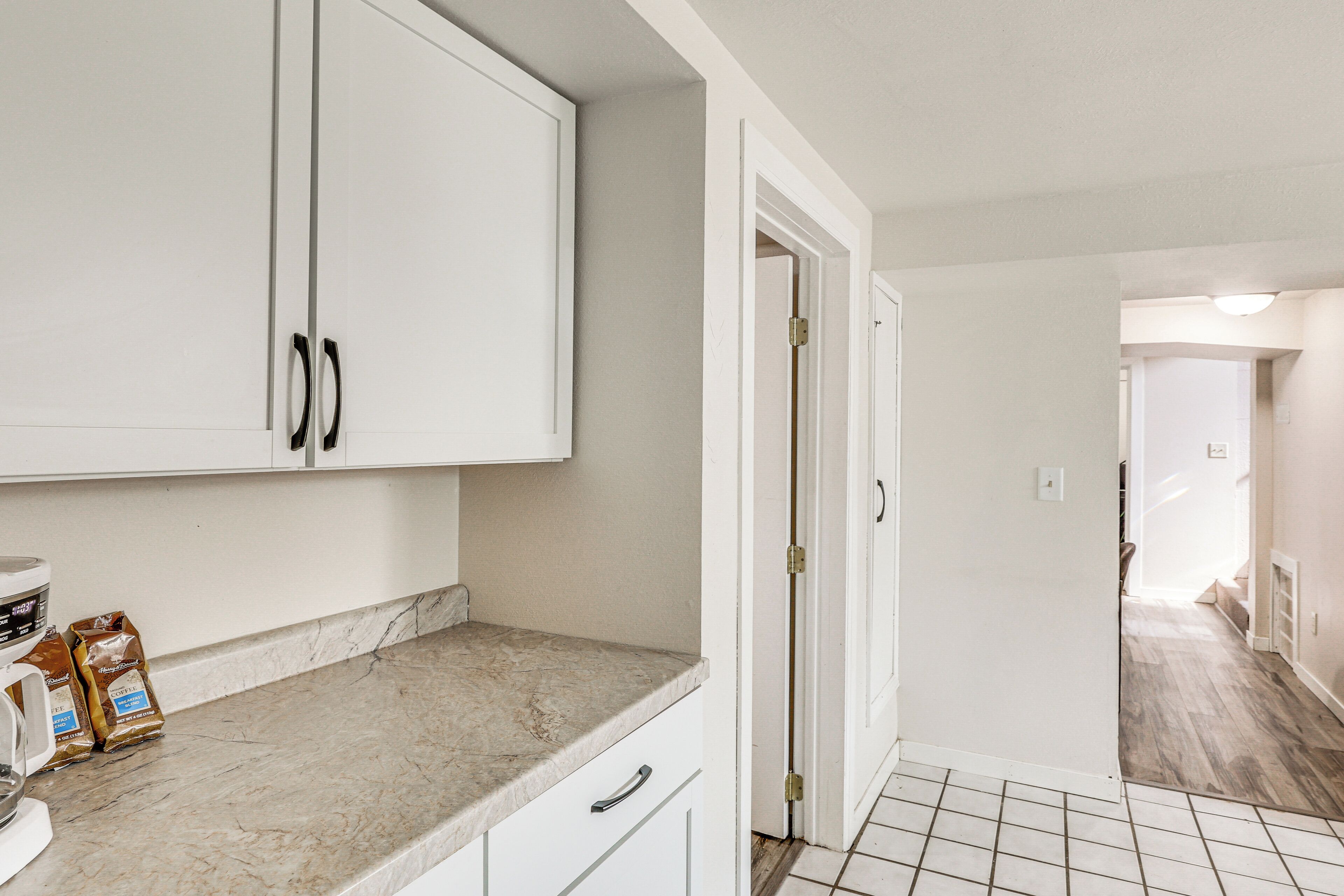 A kitchen with white cabinets, a marble countertop, and a tiled floor.