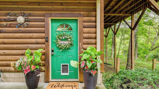 A wooden cabin with a green door, a welcome mat, and two potted plants. - Riverfront Rutherfordton Retreat w/ Fire Pit! (Rutherfordton)