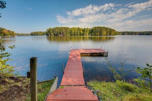 A wooden dock extending into a calm lake surrounded by trees. - Rhinelander Chain of Lakes Home w/ River Dock! (Rhinelander)
