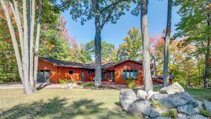 A rustic cabin with a wooden exterior, surrounded by large rocks and trees. - Rhinelander Chain of Lakes Home w/ River Dock! (Rhinelander)