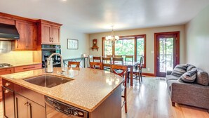 A spacious kitchen with granite countertops, wooden cabinets, and a dining area with a chandelier. - Rhinelander Chain of Lakes Home w/ River Dock! (Rhinelander)