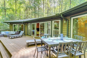 A wooden deck with outdoor furniture, a dining table with chairs, and a glass-enclosed patio area. - Creekside Cabin Rental ~ 8 Mi to Downtown Ellijay! (Ellijay)